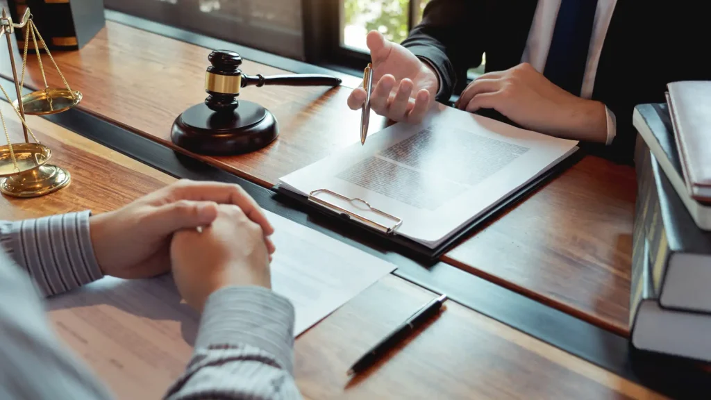 Lawyer discussing legal documents with a client at a desk with a gavel.