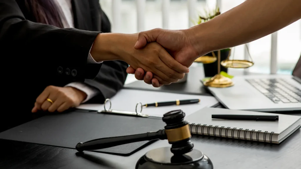 Close-up of a handshake between two people with a gavel in the foreground.